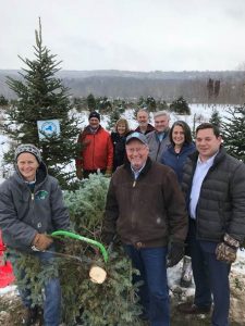 NYS Agriculture Commissioner Richard A. Ball, center, cuts a Christmas tree at Rocking Horse Christmas Tree Farm in Onondaga County. Photo supplied.