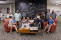 The Tipping Point team poses for a portrait in front of their Chalk Wall. (Photo provided by Tipping Point Communications)