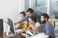 People gathered around a computer screen (Depositphotos)