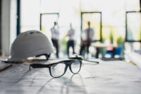 Glasses and a hardhat on a blueprint (Depositphotos)