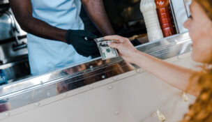 Woman handing cash after ordering by Depositphotos