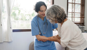 senior care professional helping elderly resident by Depositphotos